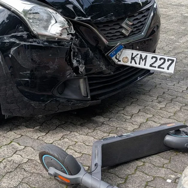 Voiture accidentée à l'avant, optique et pare-chocs abîmés, trottinette couchée sur les pavés